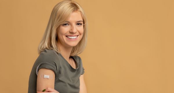 Junge Frau nach der Impfung mit Pflaster auf dem Oberarm.