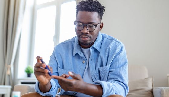 Mann in den 30ern misst seinen Blutzuckerspiegel.