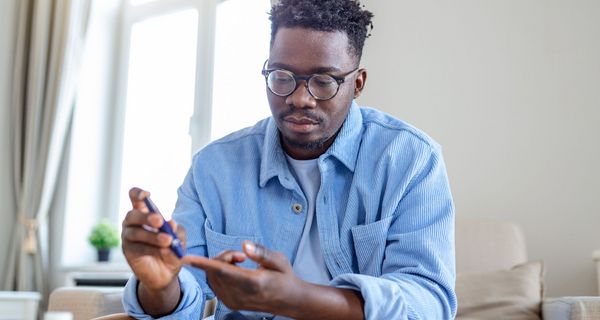 Mann in den 30ern misst seinen Blutzuckerspiegel.