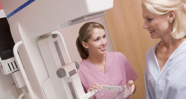 Jüngere Frau erklärt einer älteren, wie die Mammografie ablaufen wird