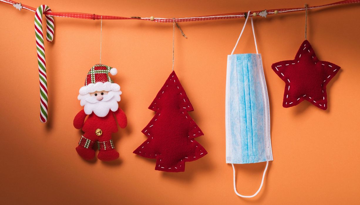 Eine Zuckerstange, Weihnachtsdekoration und eine OP-Maske hängen an einer Leine.
