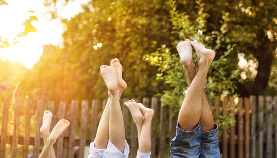 Familie mit zwei Kindern, strecken alle ihre Beine in die Luft.