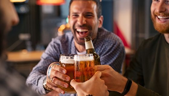 Drei Männer, stoßen mit Bier an.