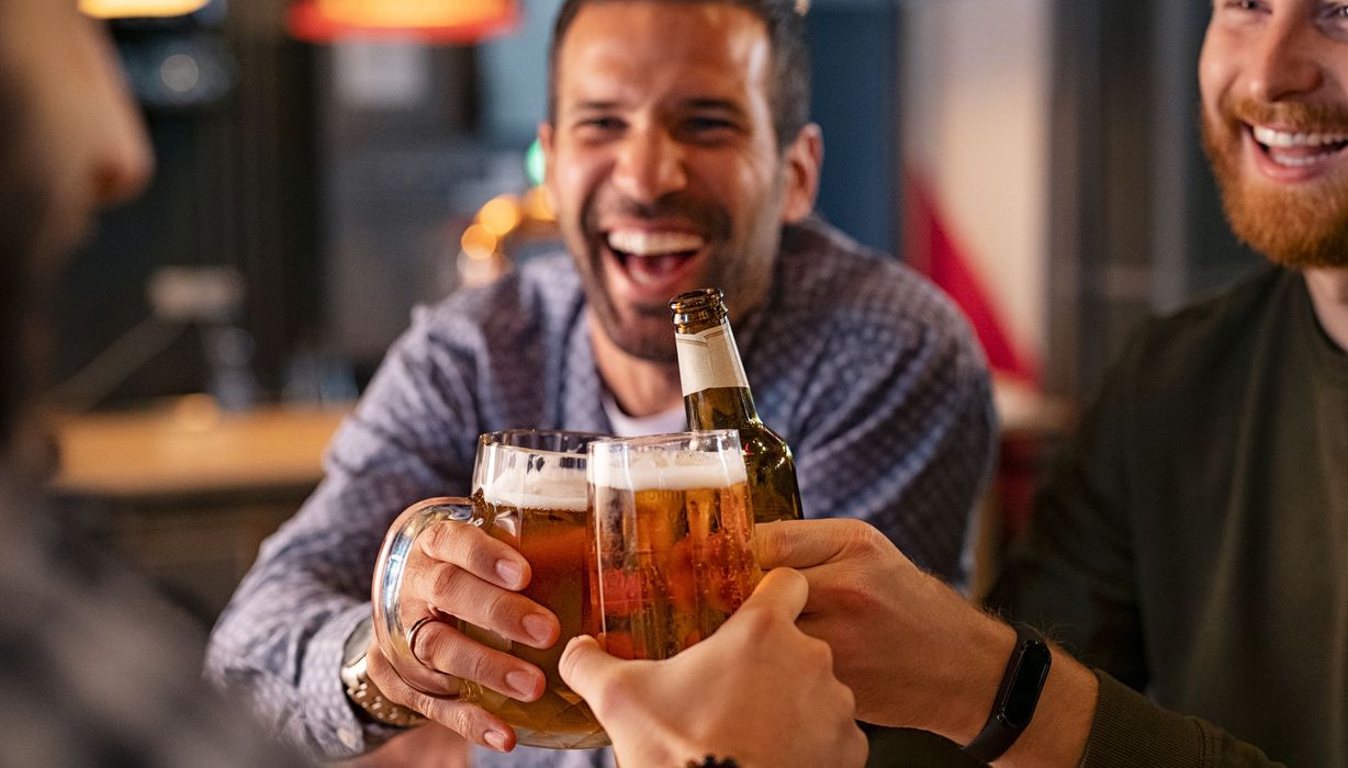 Drei Männer, stoßen mit Bier an.