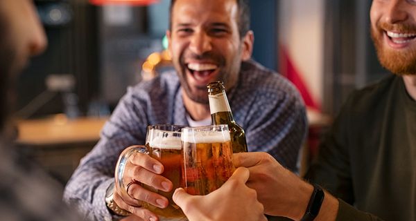 Drei Männer, stoßen mit Bier an.