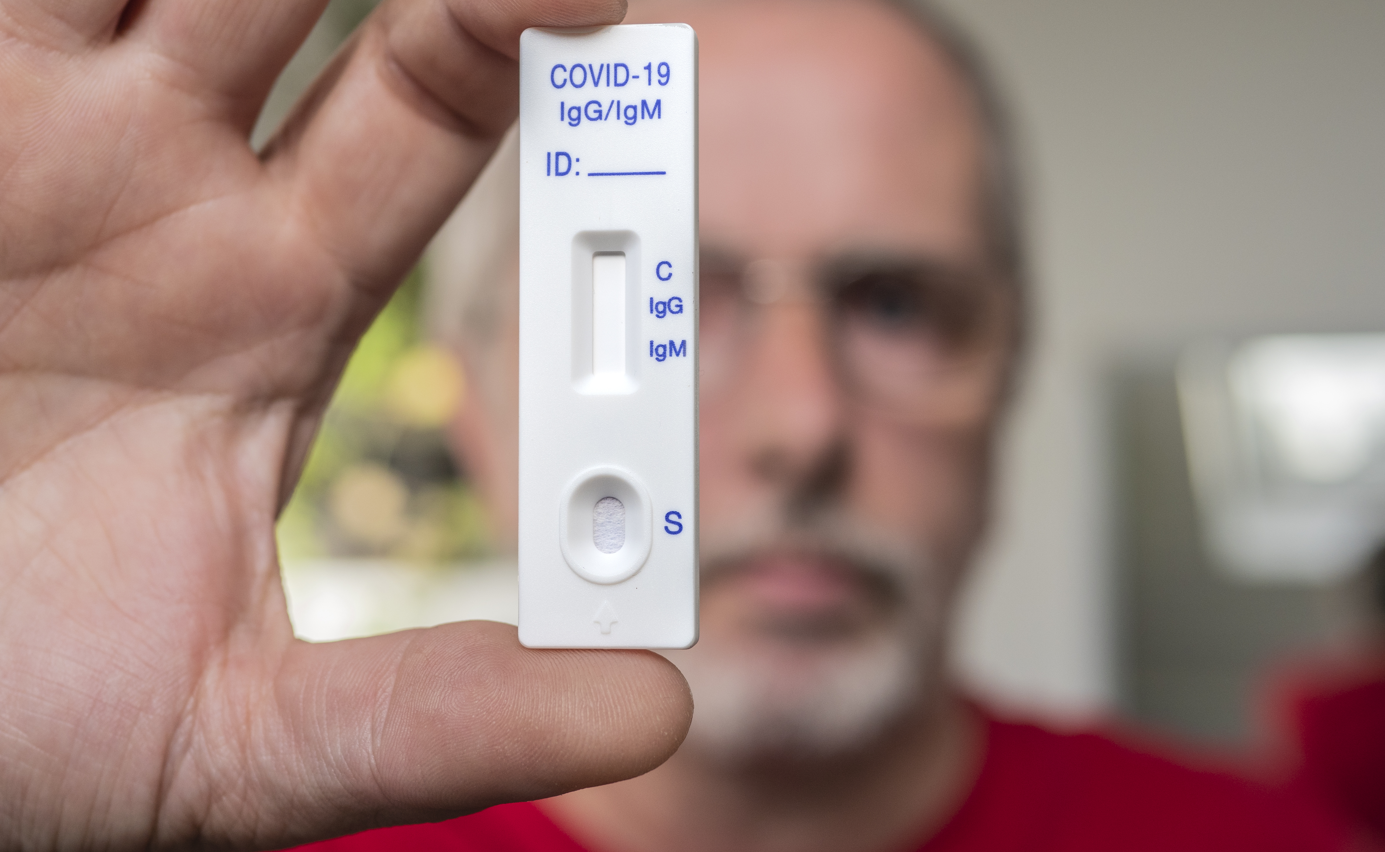 Mann hält einen Covid-19-Schnelltest in die Kamera