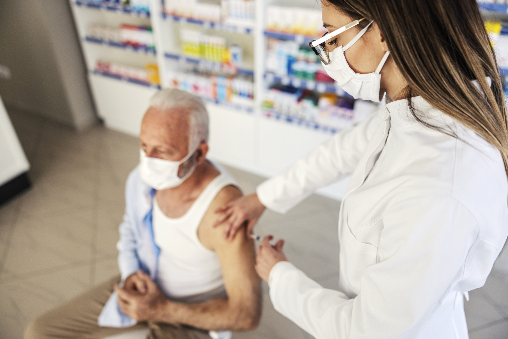 Apothekerin impft einen Patienten.