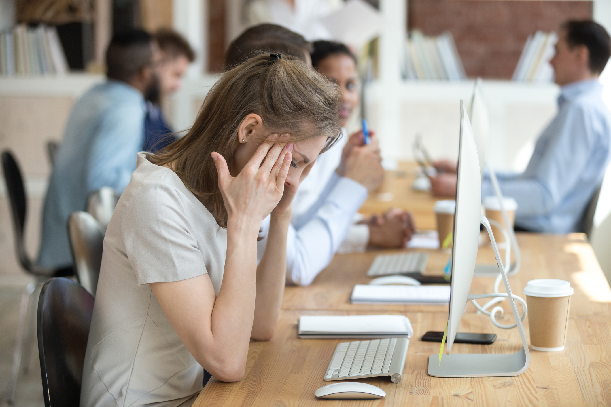 Junge Frau, sitzt müde vor ihrem Computer im Büro.