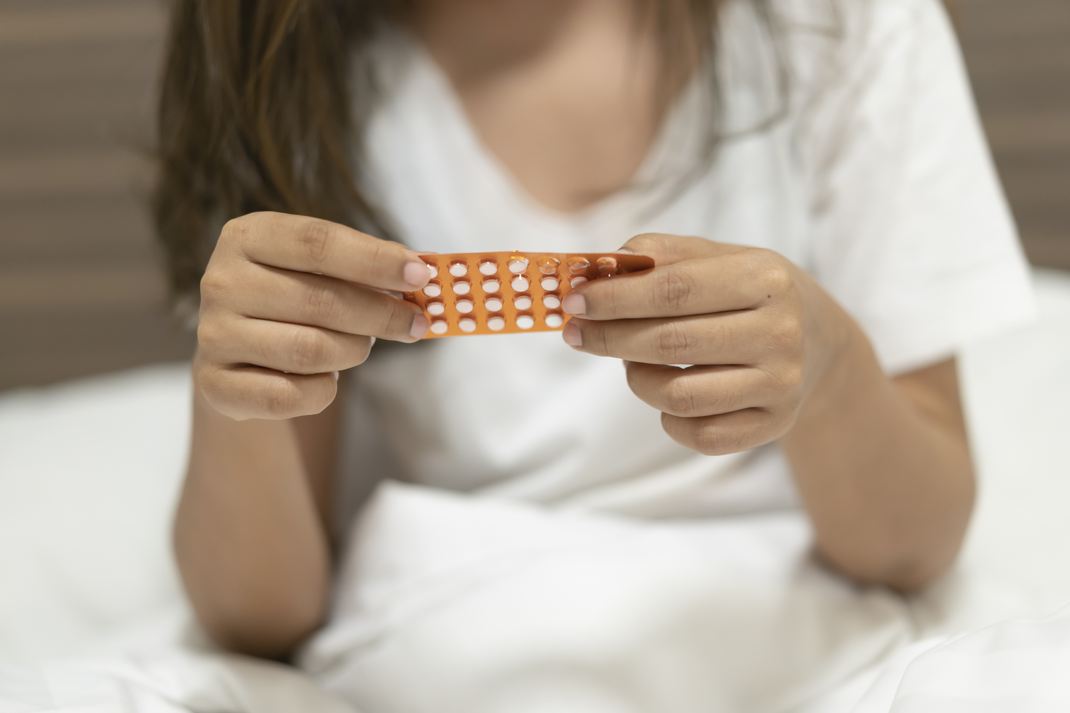 Eine Frau hält mit ihren Händen einen Monatsblister von der Minipille in der Hand.